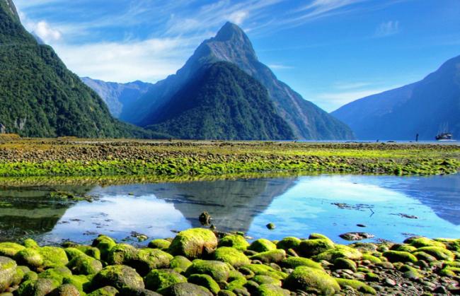 Mountain reflected in clear water beside a green valley
